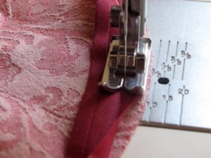 Sew single fold bias tape to right side of fabric - bias tape set in 1/8" from edge of fabric, follow fold line for seam