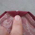 Press bias tape to wrong side of apron. At corners, press corner point down