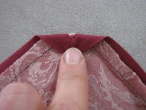 Press bias tape to wrong side of apron. At corners, press corner point down